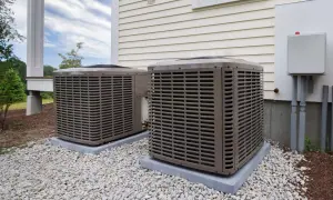 Dwa klimatyzatory przy nowoczesnym domu energooszczędnym, otoczone białym żwirem.