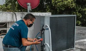 Technik sprawdza czujnik ciśnienia klimatyzacji za pomocą manometru.