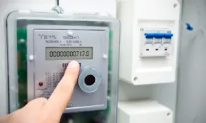 Palec wskazuje licznik prądu, pokazując jak odczytać licznik prądu Tauron. Widoczny jest numer 717.0.