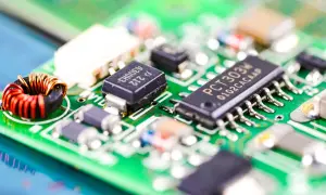 Zbliżenie na zieloną płytkę drukowaną z widocznym układem scalonym PCT303M, cewką i innymi komponentami elektronicznymi.