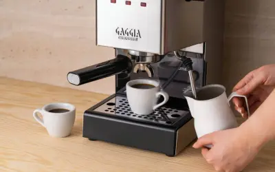 Gaggia Classic w rankingu ekspresów do kawy do 2000 zł. Parzy kawę do filiżanki, obok dzbanek na mleko.