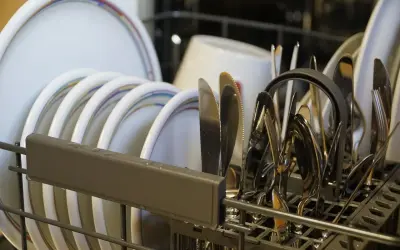 Zmywarka Amica z błędem E4. W koszu piętrzą się talerze i sztućce, czekając na rozwiązanie problemu.