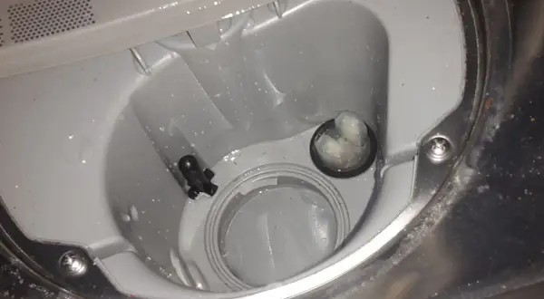 Zmywarka Beko, błąd E01. Widoczny filtr i odpływ z resztkami jedzenia, które mogą powodować problem.
