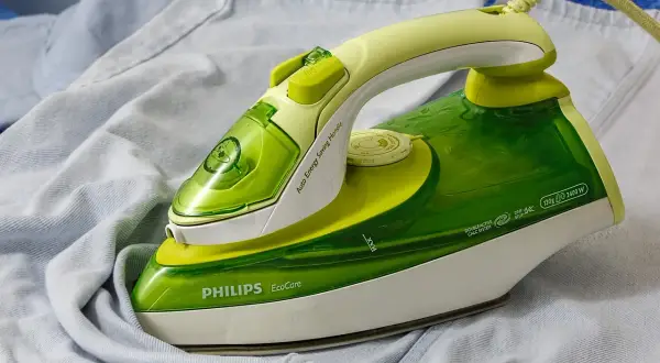 Zielone żelazko Philips EcoCare na jasnych ubraniach. Dowiedz się, jak wyczyścić żelazko, by prasowanie było efektywne.