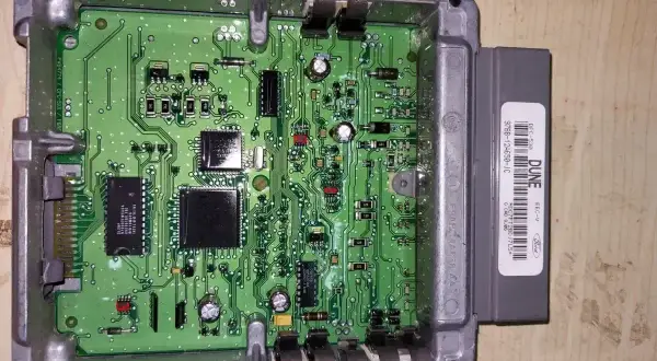 Elektroniczny moduł sterujący silnika Forda, prawdopodobnie z funkcją immobilizera, z widoczną zieloną płytką drukowaną i szarym złączem.
