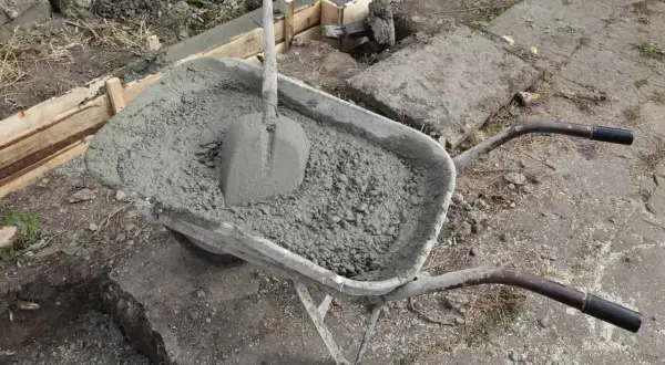 Taczka z betonem i łopatą, gotowa do wylania uziomu fundamentowego.