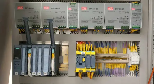 Panel sterowania z zasilaczami MW DRT-240-24, sterownikiem Siemens S7-1500 i żółtymi przewodami. Akpia.