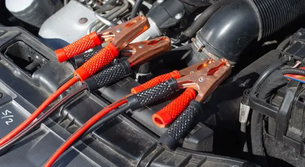 Kable rozruchowe podłączone do akumulatora, bo auto nie odpala. Czerwone i czarne kable z zaciskami.