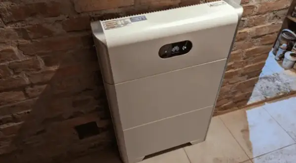 Biały magazyn energii 10kW, stojący przy ceglanej ścianie, to serce domowej instalacji fotowoltaicznej. Zastanawiasz się, na ile wystarczy energii z takiego magazynu?