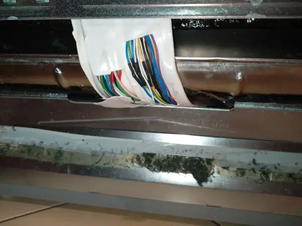 Zmywarka Beko błąd E02: widoczne uszkodzone przewody i brud pod metalową osłoną.